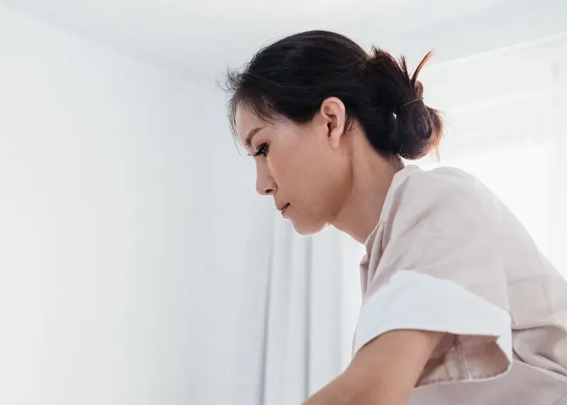 Una limpiadora prepara la cama de un apartamento con luz natural